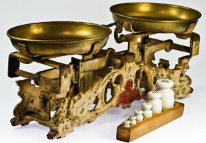 Photo of an old-fashioned brass balance scale with selection of weights in front of it