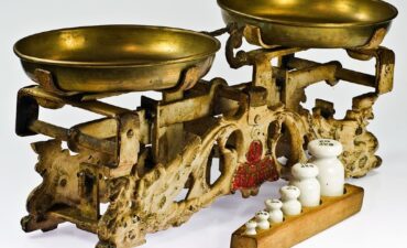 Photo of an old-fashioned brass balance scale with selection of weights in front of it