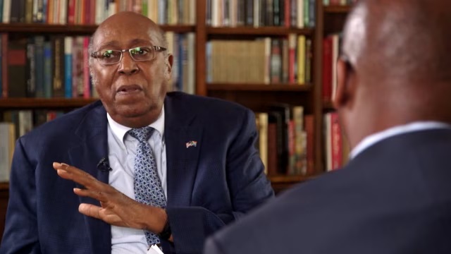 Charles Hamilton faces interview Frederick Harris in library setting