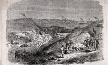 Woodcut shows men and mules resting from digging embankment above railway tracks with smoke rising from various other camps in the distance.