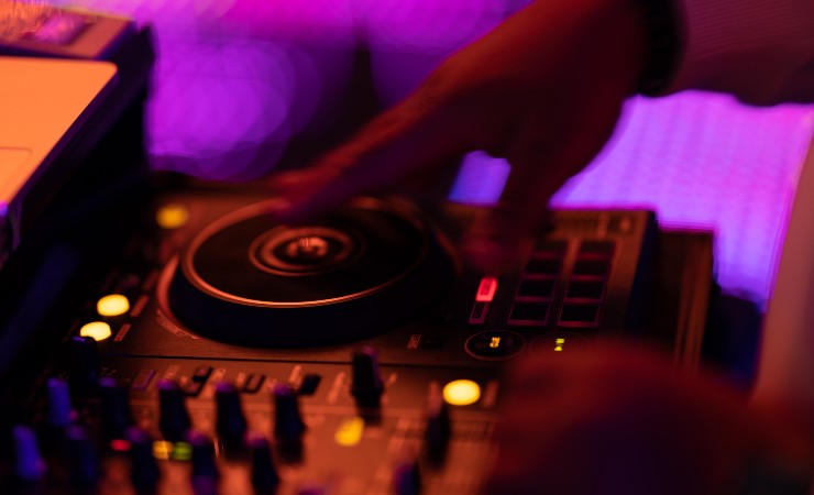 Image: Blurry close-up of a DJ scratching a record at a turntable.