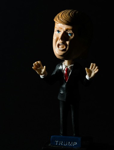 Bobblehead doll of Donald Trump against shadowy background