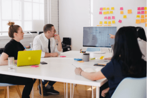 workers cluster around screen at end of table