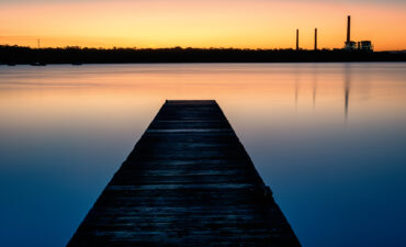 At dusk, pier on lake leads off to abrupt end