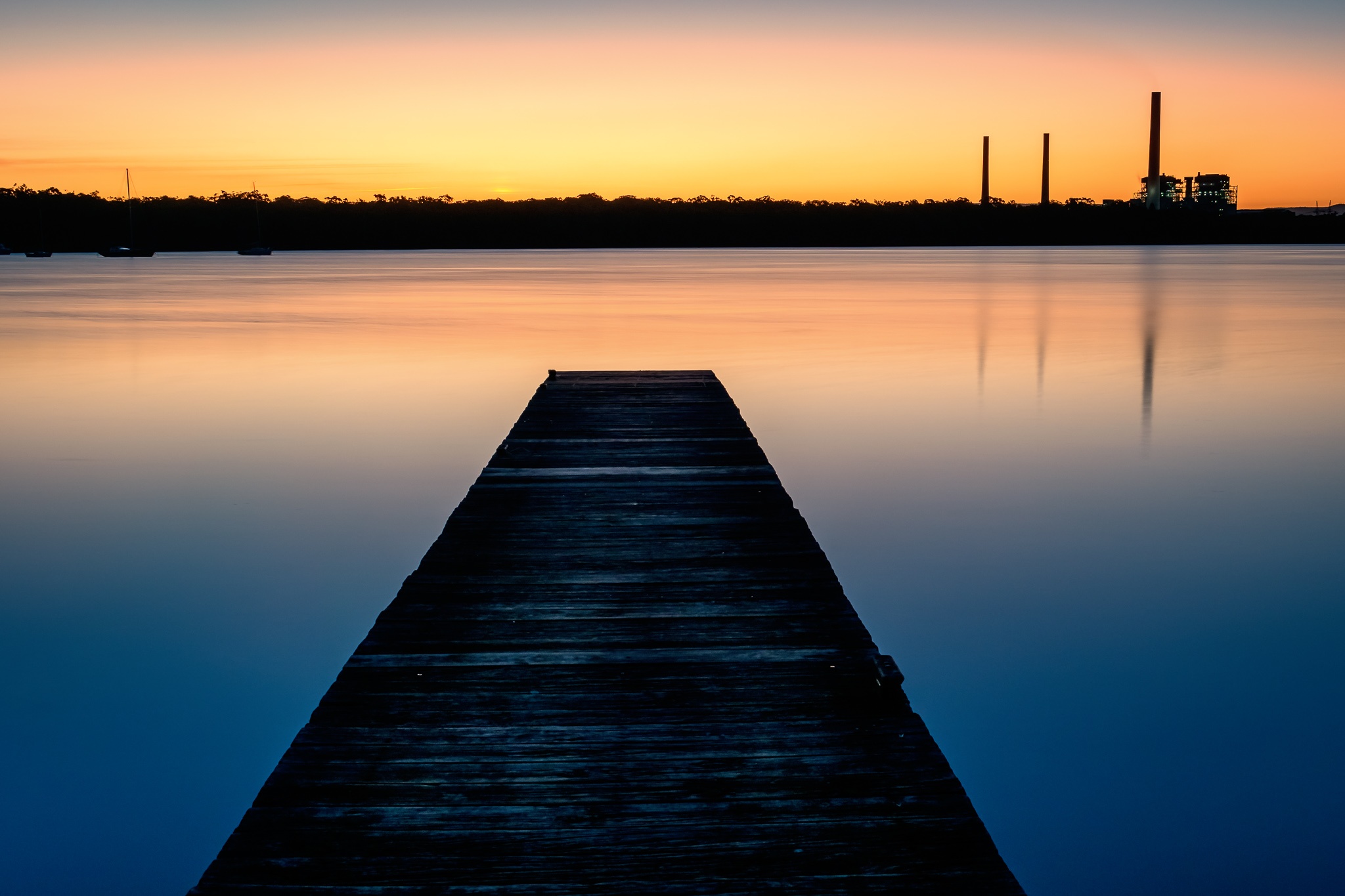 At dusk, pier on lake leads off to abrupt end