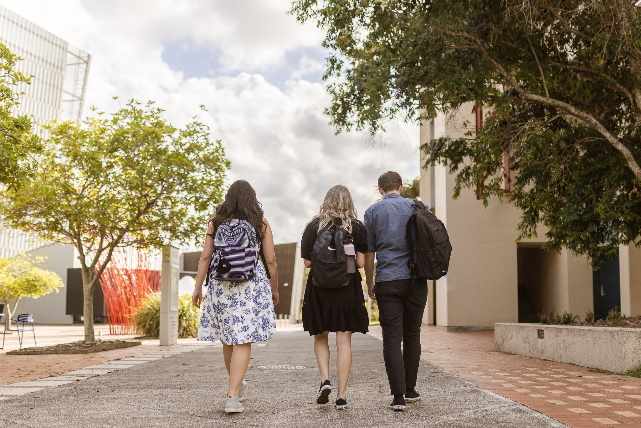 Three individuals walking on academic campus.