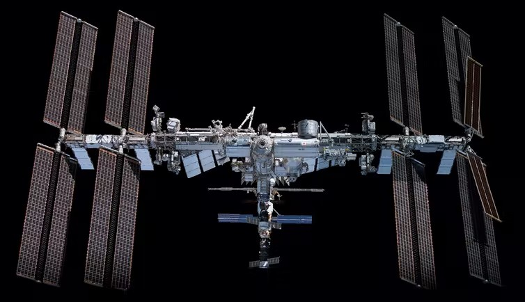 Horizontal view of International Space Station in space with all solar panels deployed