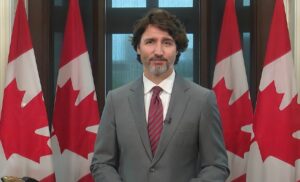 Justin Trudeau in 2021, flanked by Canadian flags