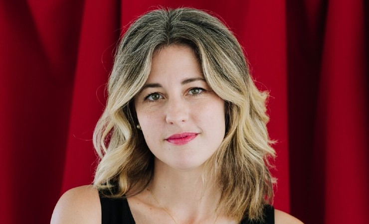 Headshot of Kathryn Paige Harden against red curtains