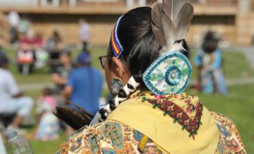 Woman seen from behind and dressed in clothing reflecting quebec first nations style