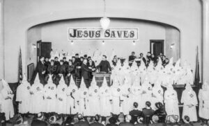 Hooded Ku Klux Klan members beneath Jesus Saves sign