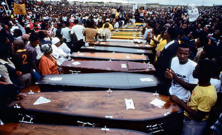 mourners surround a long line of coffins