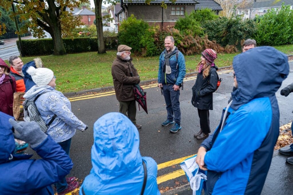 Group of people dressed in light rain gear circled around leader on public street