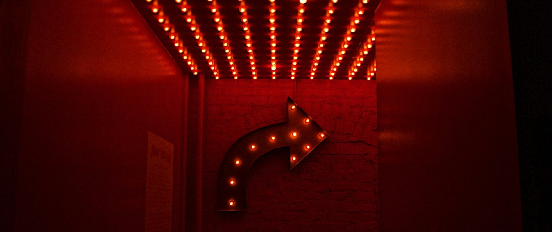 Giant arrow with light bulbs attached points way to right on garish arcade