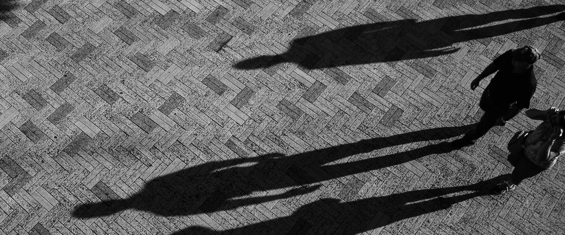 Tourists in public square marked by long shadows on ground