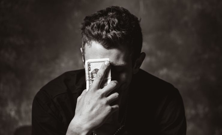 Distressed man holds stack on money to forehead