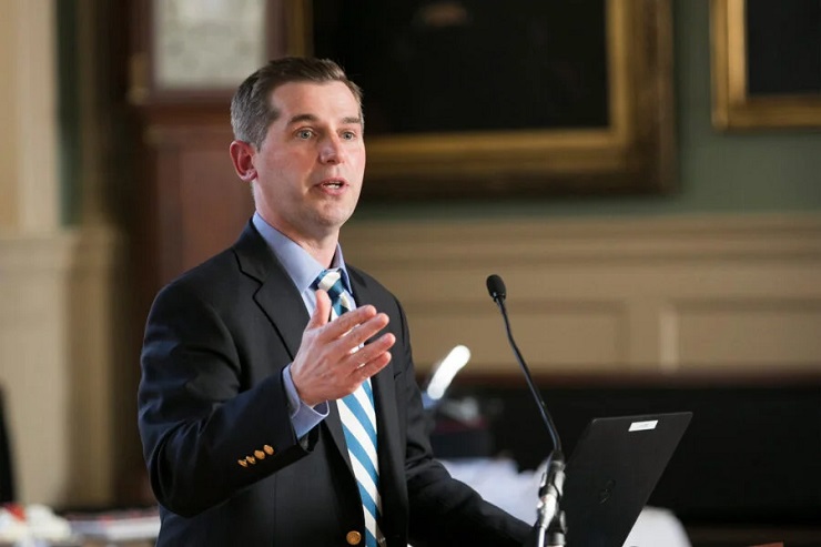 Mathew Nock in suit talks at event in ornate room