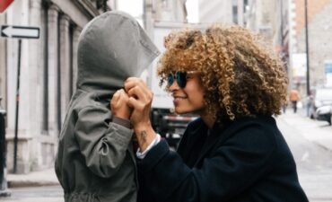 Woman talking with child in hoodie in big city