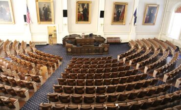 Empty government chamber with seats concentrically placed in semicircle and impressive desk at center