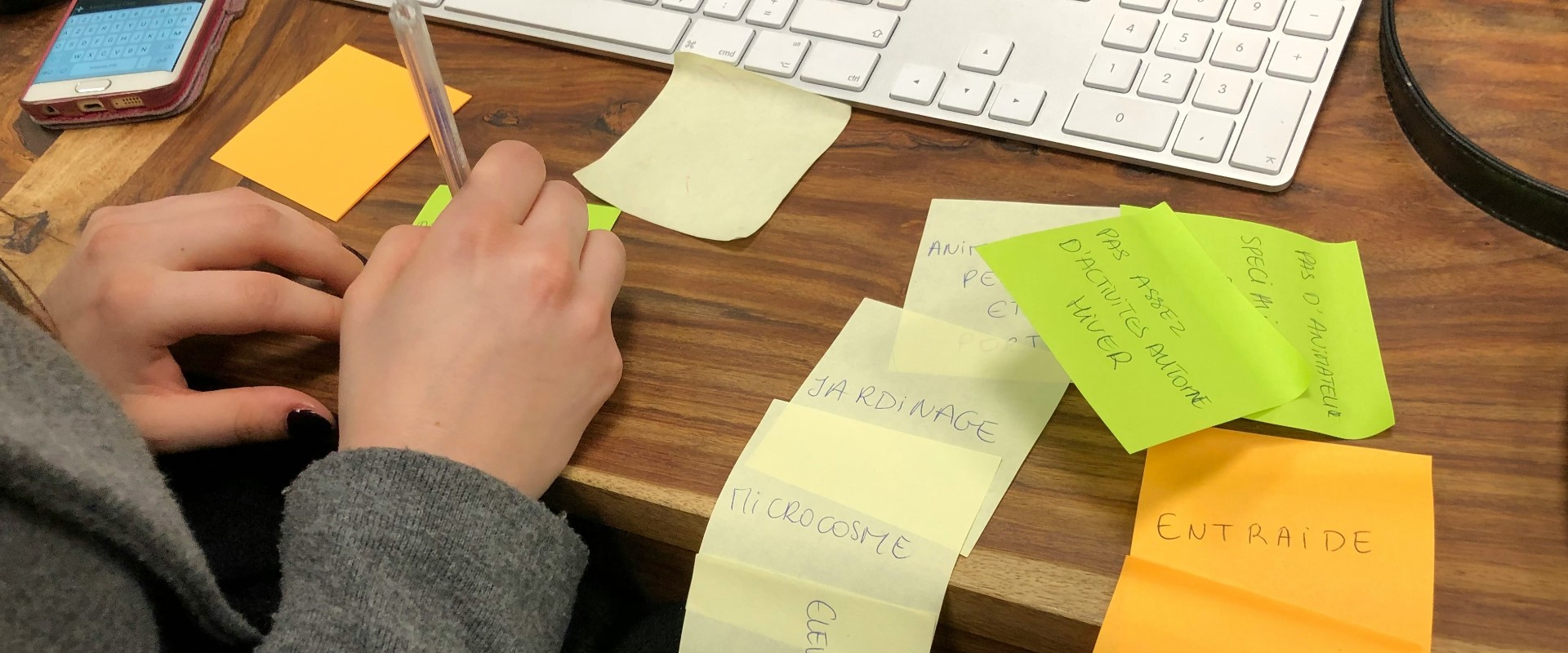 Wom's hand show writing down future actions on post-it notes on desk