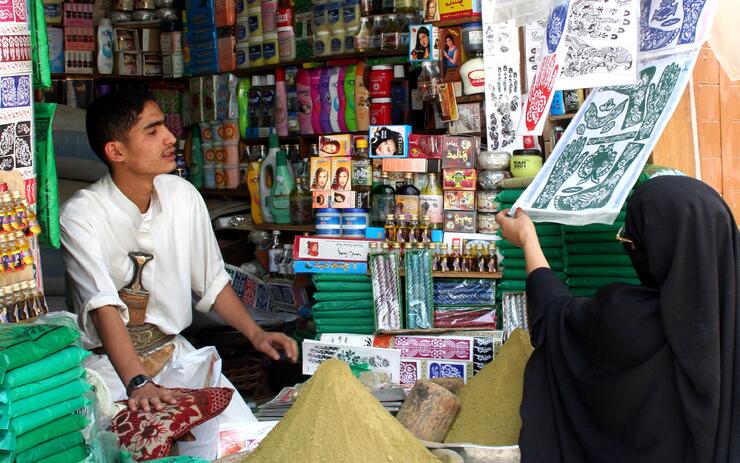 Shopkeeper at small stall in Yemen serves female shopper
