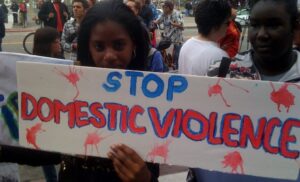Young woman at rally holding sign that reads 'stop domestic violence'