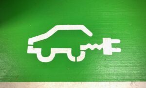 Stenciled outline of vehicle connected to a power adapter painted on a green wall.