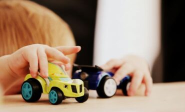 Close-up photo of child playing with toy cars.