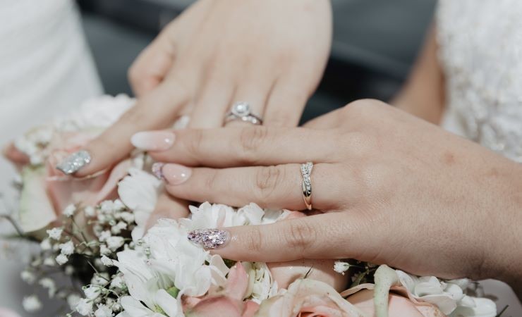 Close-up image of the manicured hands of two brides.