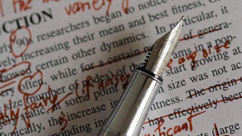 A quill pen sits on a hand-edited manuscript