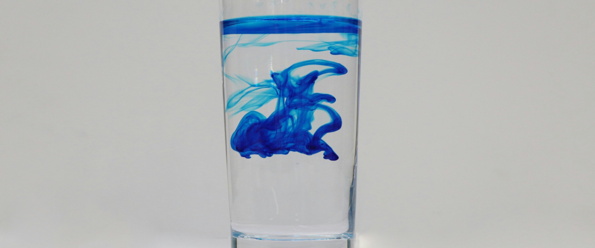 Blue stain spreading in glass of pure water
