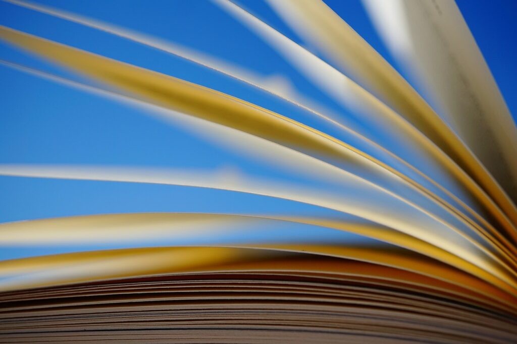 Photo of book pages flipping against a blue background.