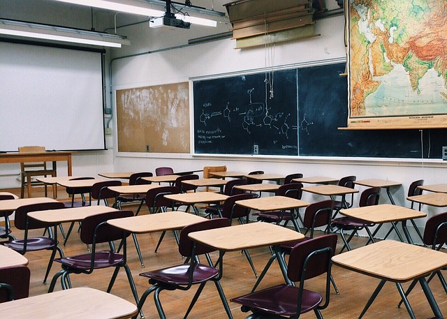 Photo of a classroom with rows of desks and a chalkboard on the wall.