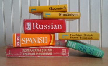 Photo of textbooks for various different languages stacked on top of each other.