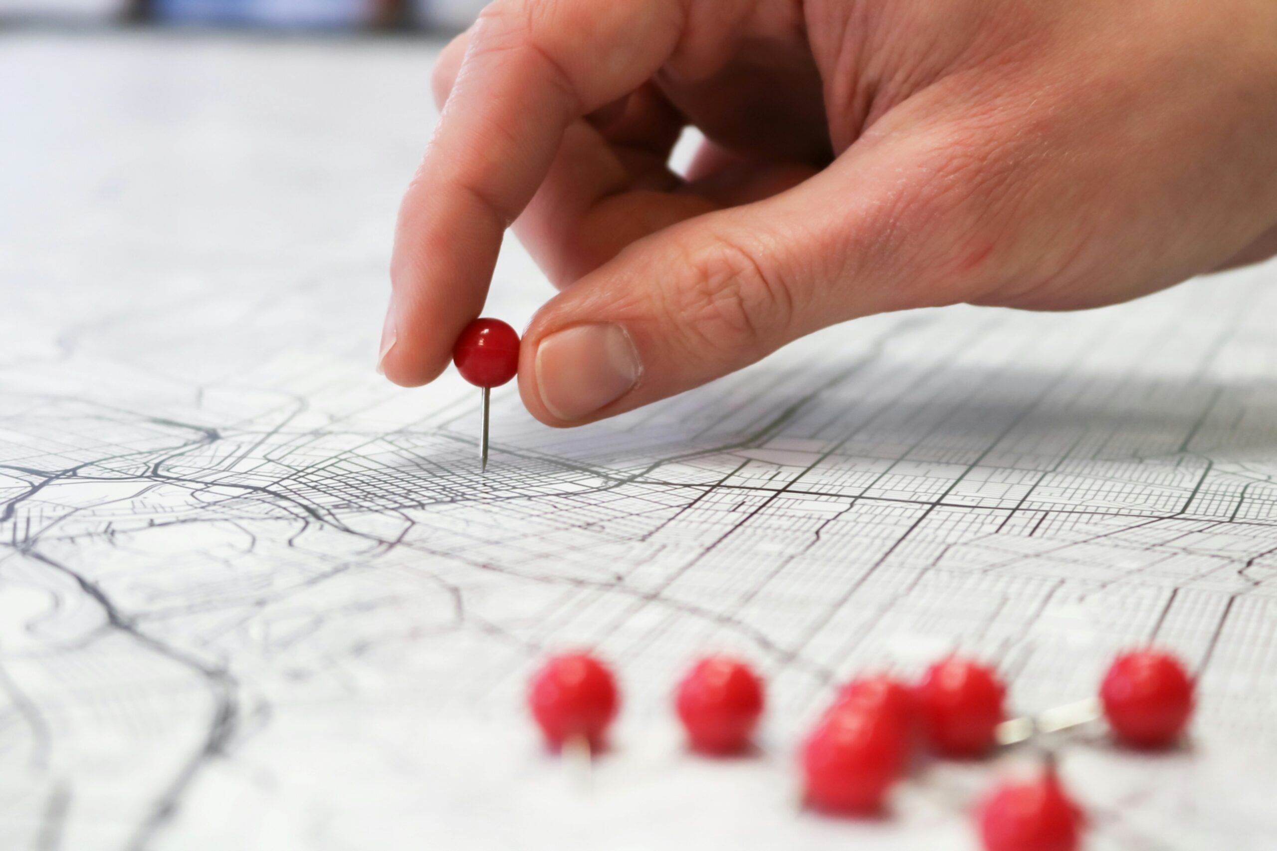 Person placing red push pins into city street map.