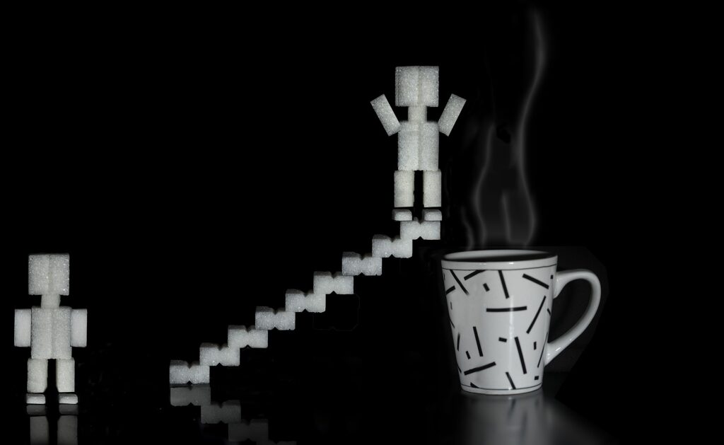 Sugar-cube figure on sugar cube stairs about to jump into steaming coffee