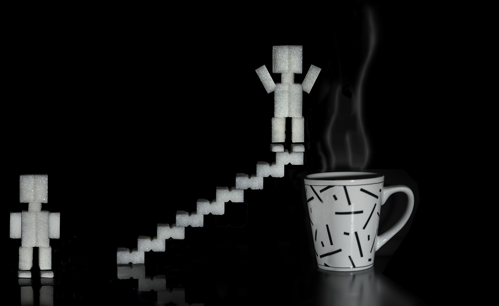 Sugar-cube figure on sugar cube stairs about to jump into steaming coffee