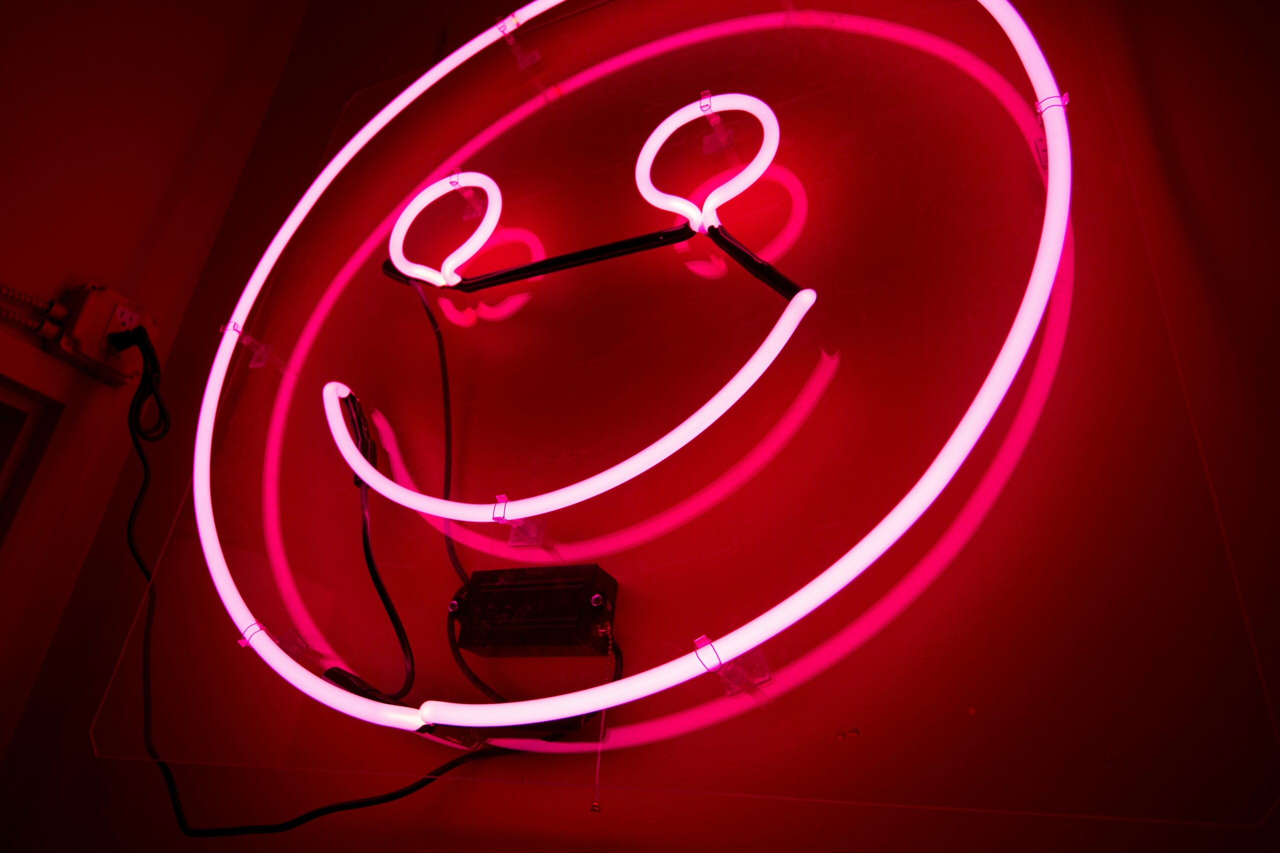 A pink neon sign in the shape of a smiley face