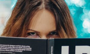 Woman looking over top of book with anger in her eyes