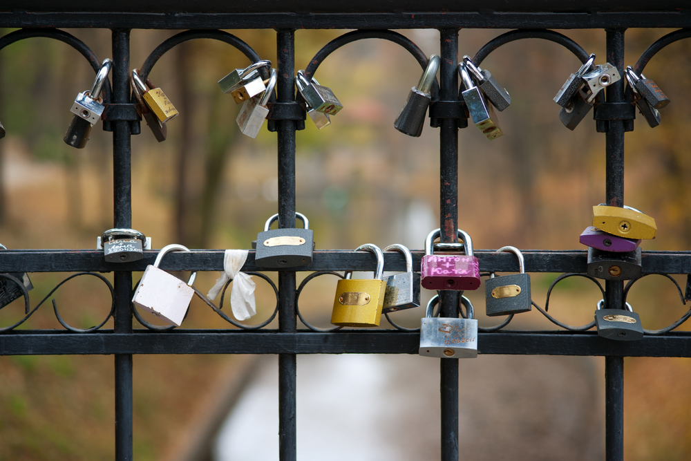 Various padlocks hanging on wrought iron gate