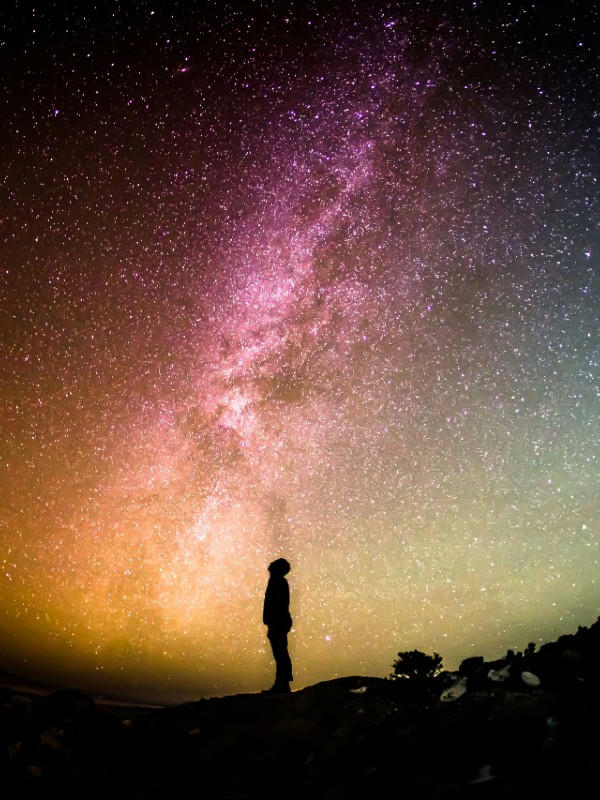 lone figure silhouetted against plethora of stars at night