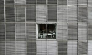 Glass office block with venetian blinds closed for all offices except two in the center