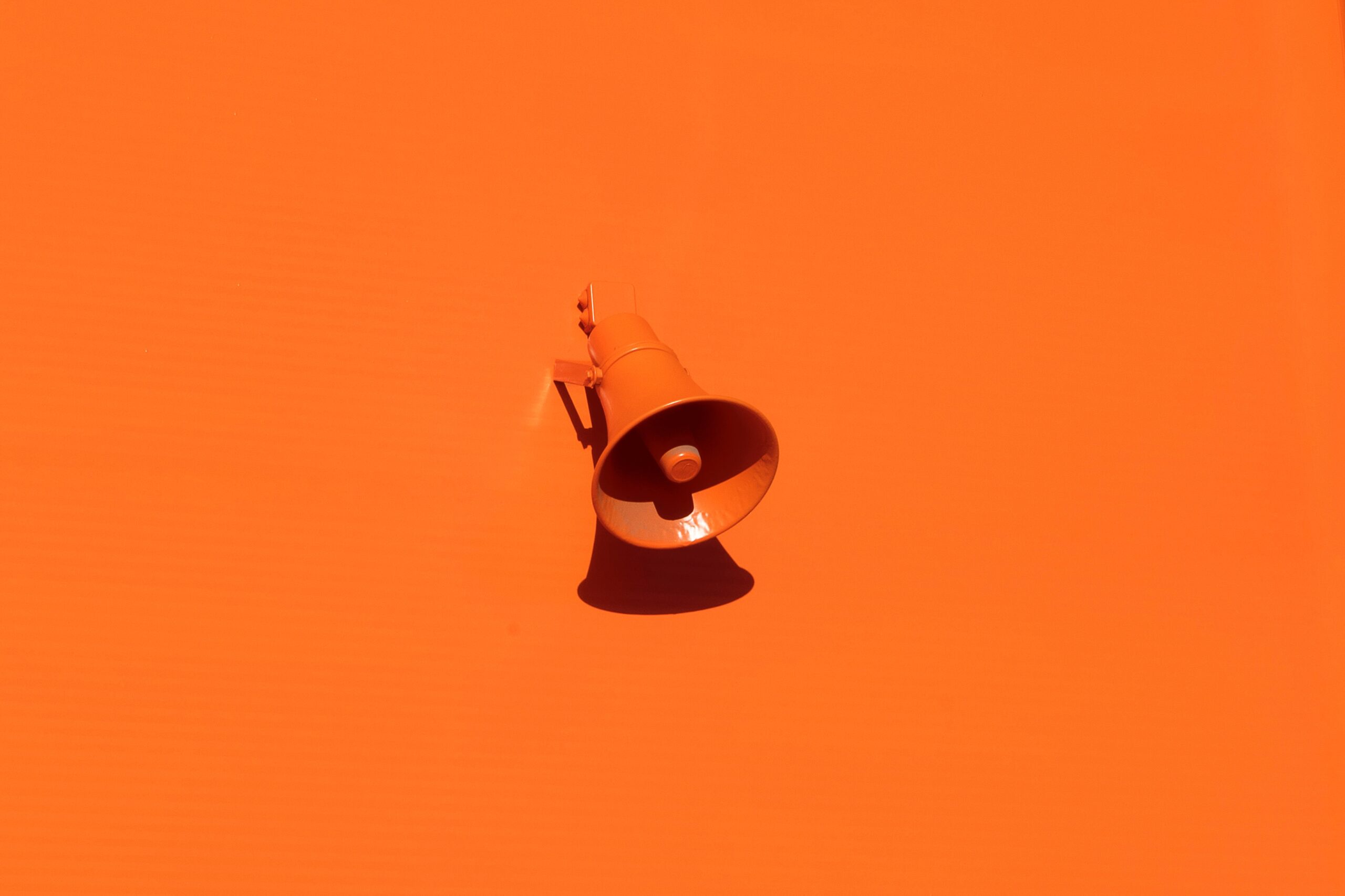 An orange bullhorn on a an orange background