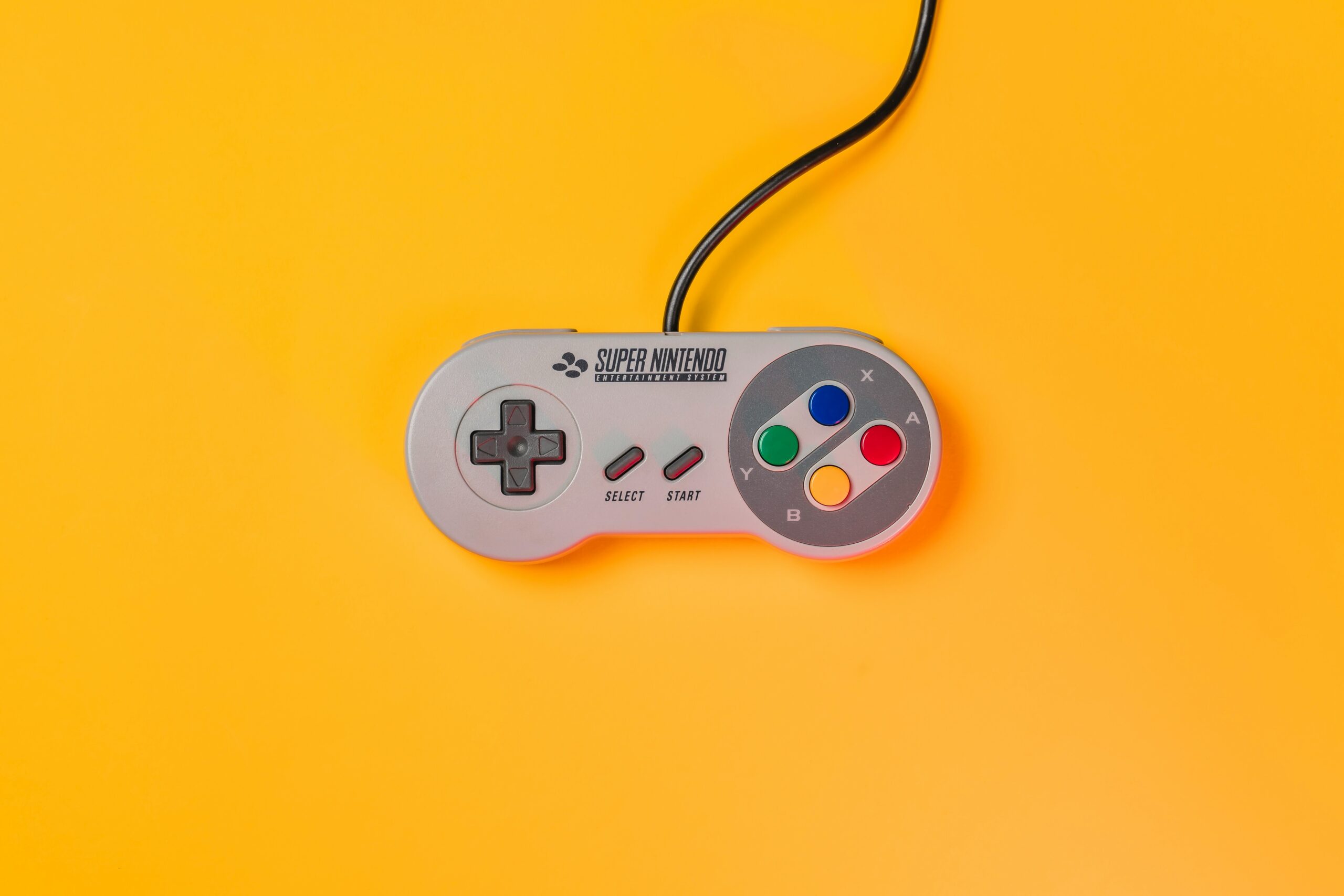 Vintage SuperNintendo controller pictured in front of a yellow background.