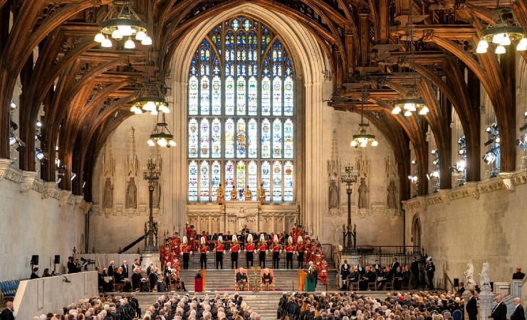 Charles and Camilla appear at the front of the cavernous Westminster Hall with stained glass window behind them