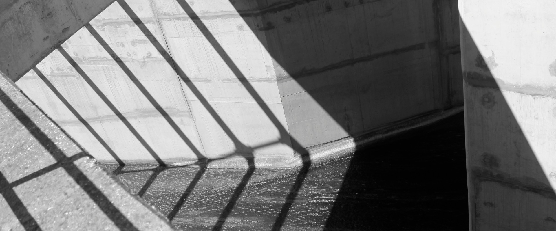Shadow of jail cell bars fall on stark concrete background