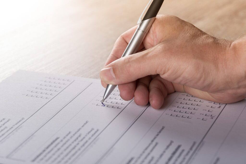 A person's hand fills out survey with pen.