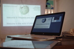 Open laptop shows Wikipedia and Wikipedia is projected on the wall.