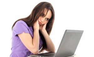 Woman holding head up while staring at laptop screen